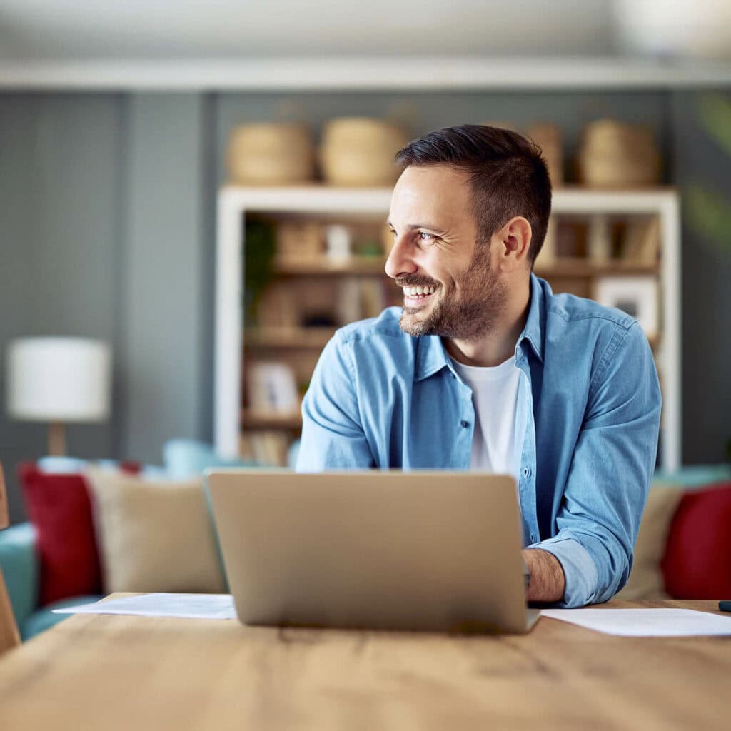 Zufriedener Mann im Homeoffice mit Laptop – stabile Glasfaser-Internetverbindung von AVACOMM für effizientes Arbeiten von zuhause.