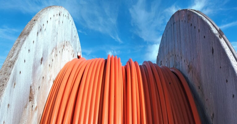Große Kabeltrommel mit Glasfaserleitungen vor blauem Himmel – Infrastruktur für Highspeed-Internet in der Region.