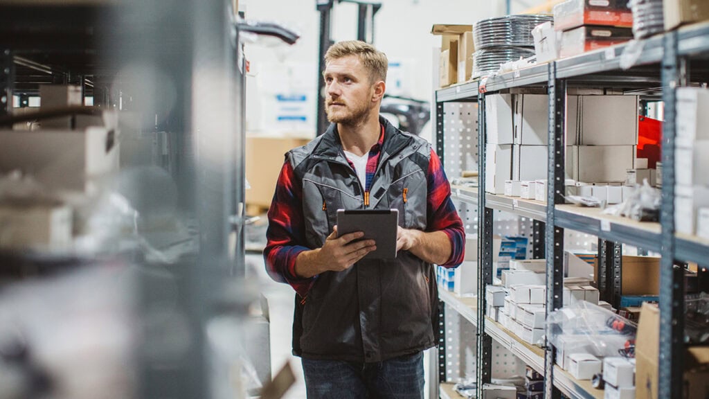Vertriebsmitarbeiter im Lager prüft den Bestand der Waren und tätigt mittels Tablet neue Bestellungen.