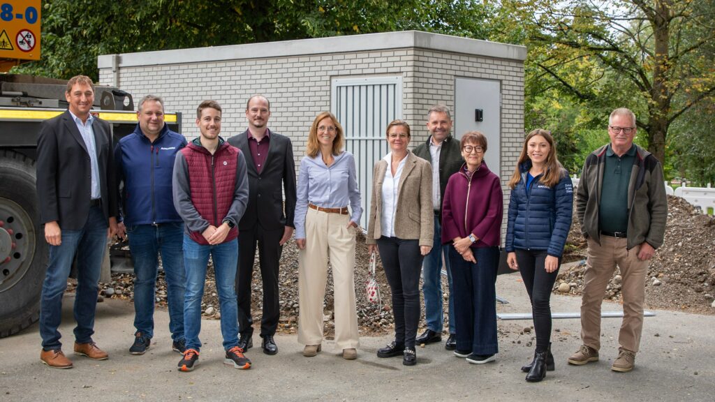 PoP Aufstellung, ein Meilenstein des Glasfaserausbaus im Achental. Vor dem garagenähnlichen Gebäude stehen v. l. Herbert Strauch (Bgm. Übersee), Thomas Astner (AVACOMM), Markus Eisenkolb (Gemeinde Grassau), Christian Gallitscher (AVACOMM), Martina Gaukler (Bgm. Staudach-Egerndach), Daniela Ludwig (2. Bgm. Grassau), Matthias Schlechter (Bgm. Reit im Winkl), Claudia Kraus (2. Bgm. Marquartstein), Julia Kisler (AVACOMM) und Ludwig Entfellner (Bgm. Unterwössen.
