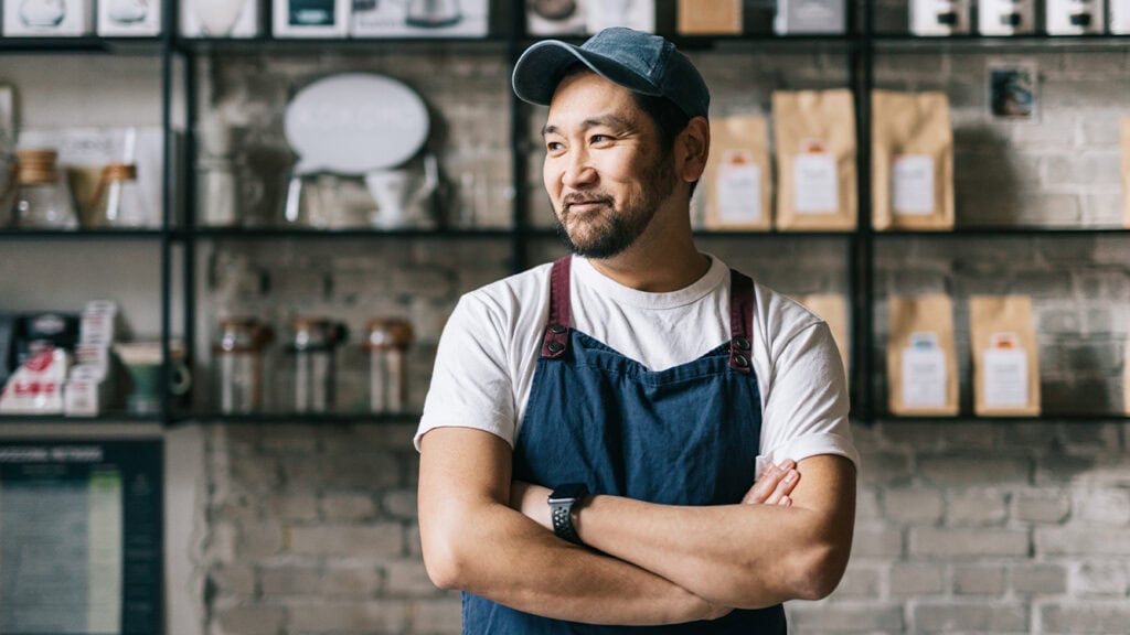 Gastronom steht mit verschränkten Armen in seinem Restaurant. Für das Gäste-WLan und seine Buchungssysteme benötigt er hohe Bandbreiten und ein stabiles Netz-